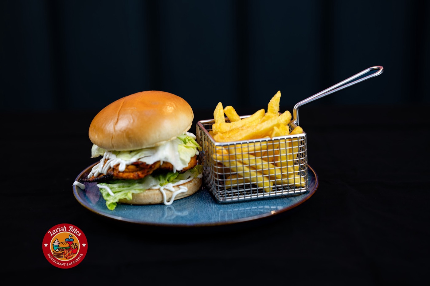 Grilled chicken burger and a basket of fries on a blue plate