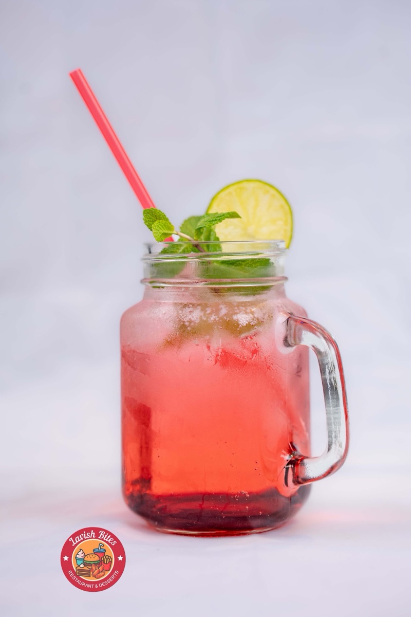 An iced mint and lime fruit cooler in a mason jar with a red straw
