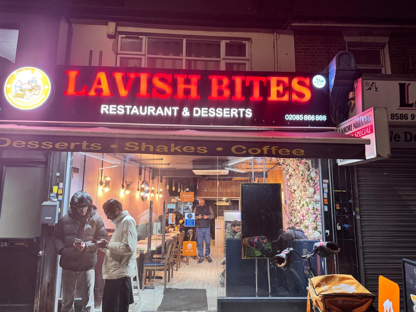 The Lavish Bites shopfront lit up in red at night on Plashet Grove, Upton Park
